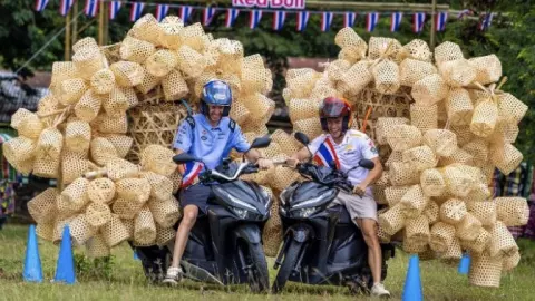 ลีลาไม่ธรรมดา “นักบิดแชมป์โลก” โชว์ทรงตัว แข่งรถสกู๊ตเตอร์บรรทุกตะกร้าไม้ไผ่ 200 ใบ (คลิป)